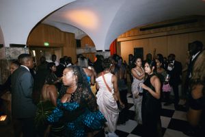 A crowded dance floor at an indoor wedding reception with people dancing under arched ceiling.