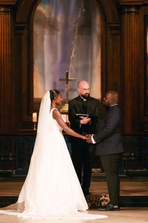 A couple exchanges vows at the altar during their wedding ceremony in front of an officiant.