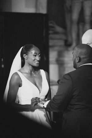 A couple exchanges rings during their wedding ceremony in black and white.