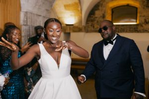 Wedding guests dance and celebrate in an elegant stone-walled venue.