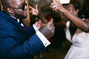Dancing guests at a wedding reception with energetic hand movements.
