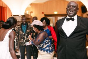 Wedding guests dancing and celebrating joyfully at an indoor reception event.