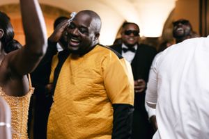 A guest in a yellow shirt laughing and celebrating at a formal event.