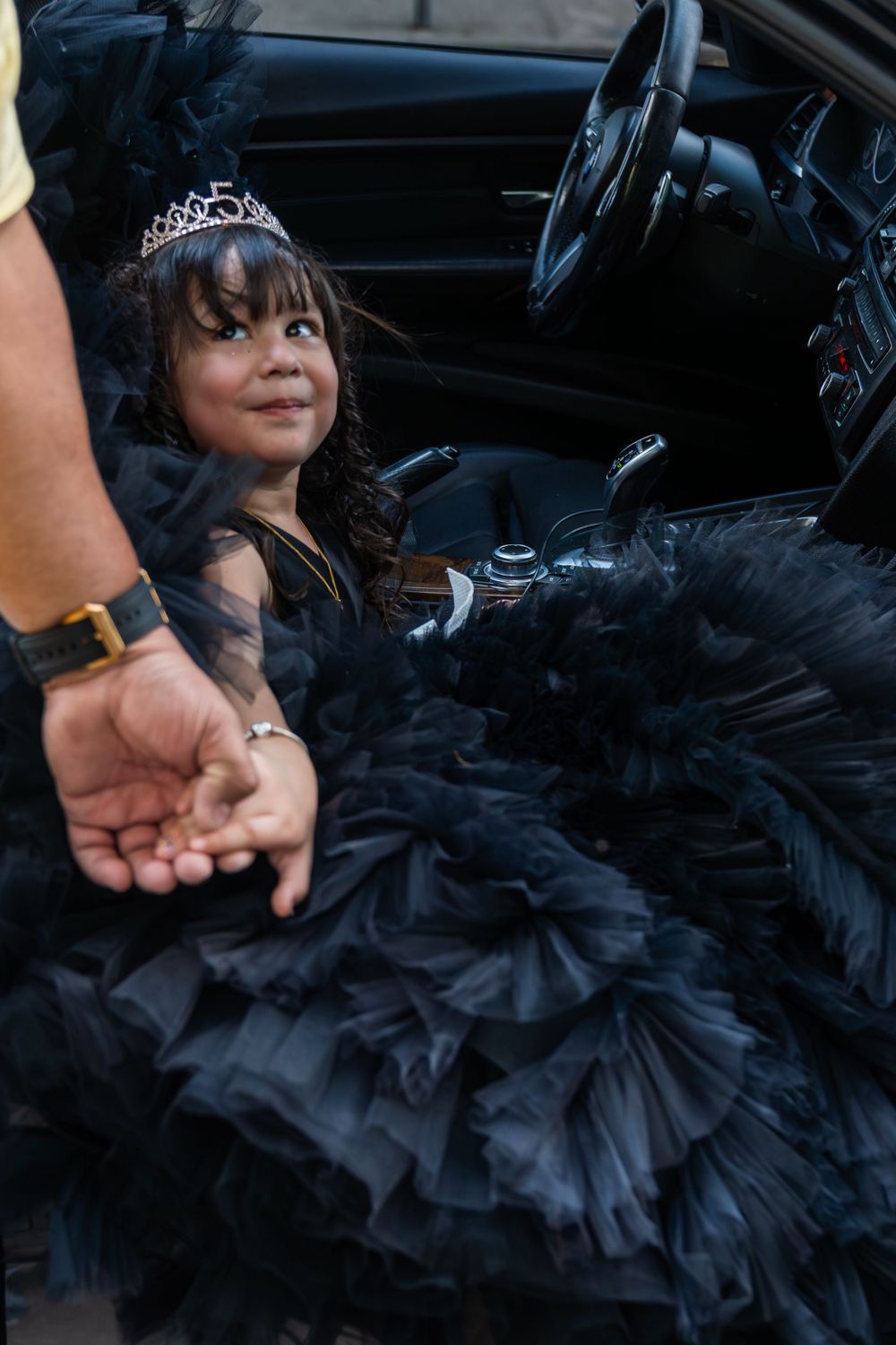 Black tulle dress fills the interior of a car while a tiara sparkles.