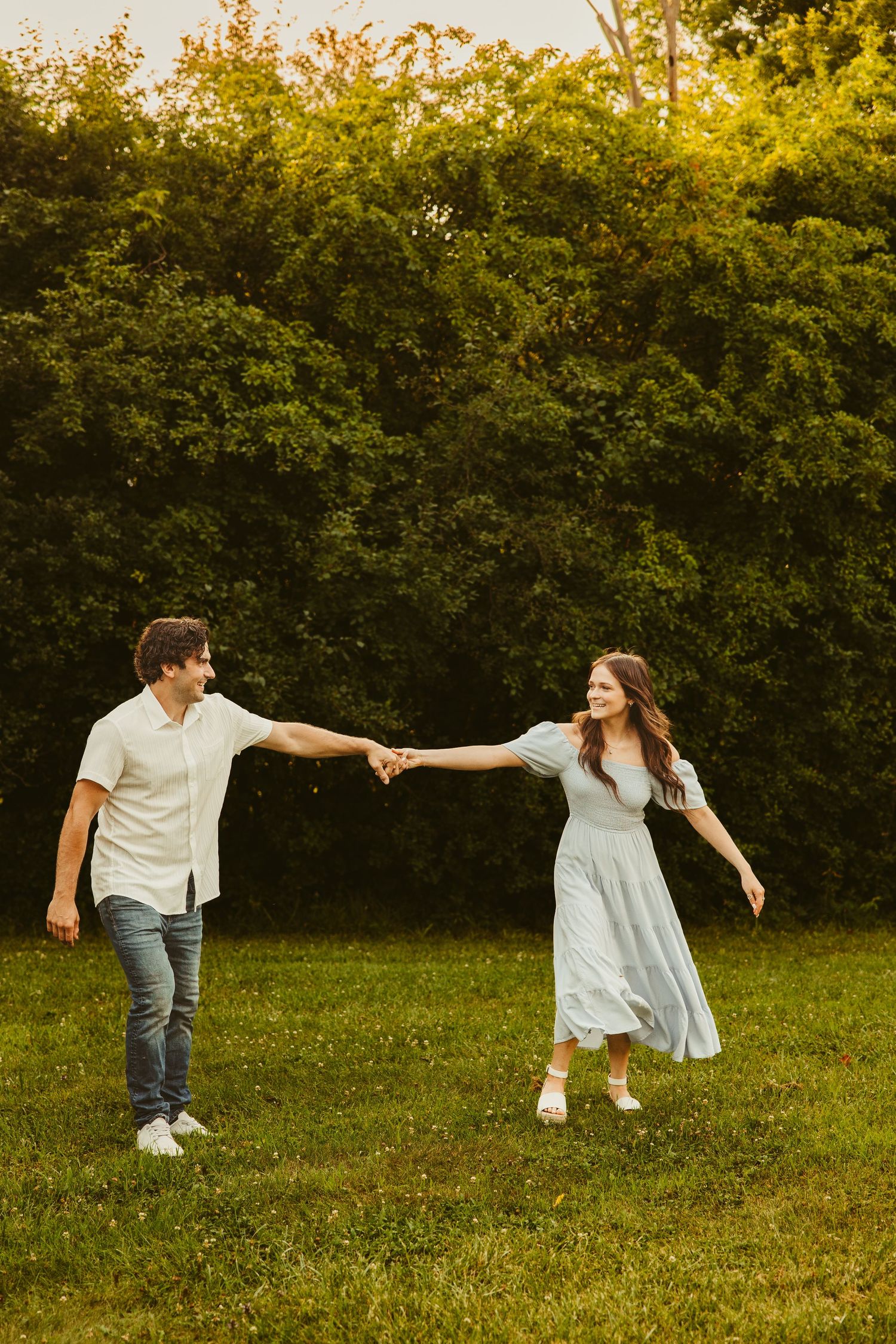 Southeast Michigan photo session shows a couple holding outstretched hands walking through a park.