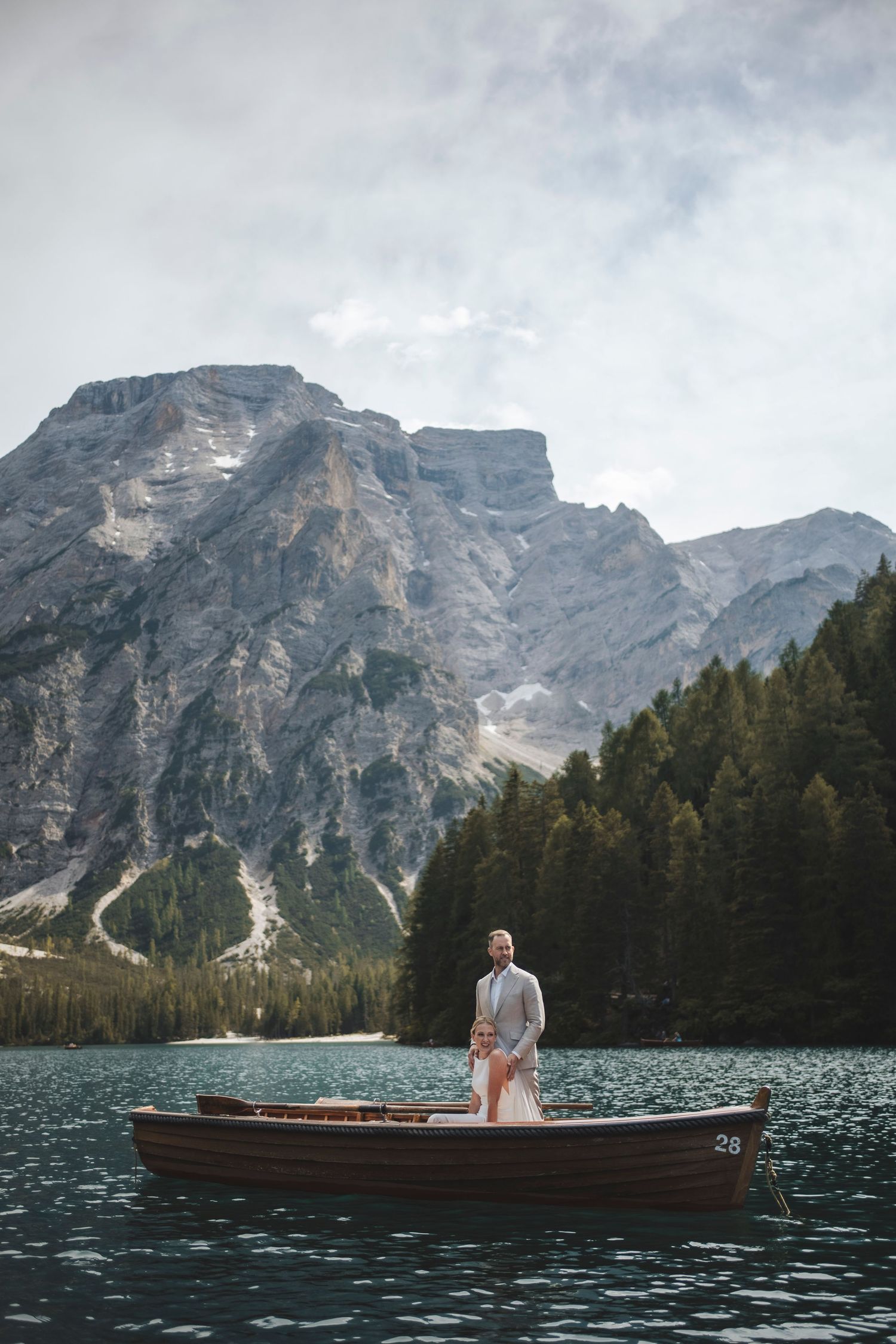 Dolomites elopement photographer capturing a bride and groom rowing a wooden boat on the emerald waters of Lago di Braies.
