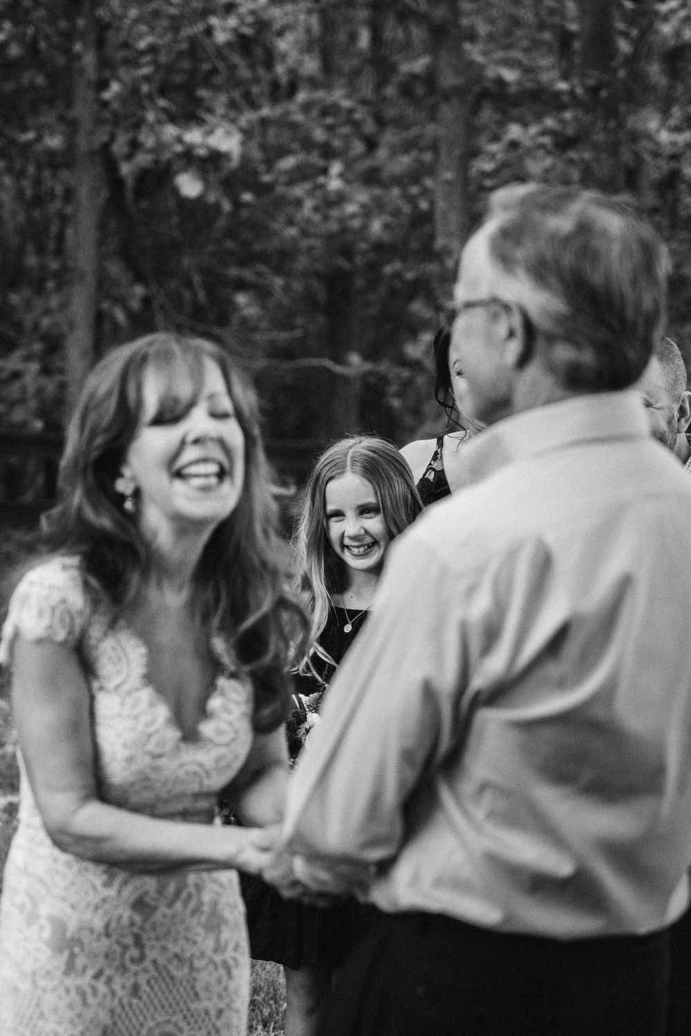 A candid black and white wedding moment showing joyful laughter during an outdoor ceremony.