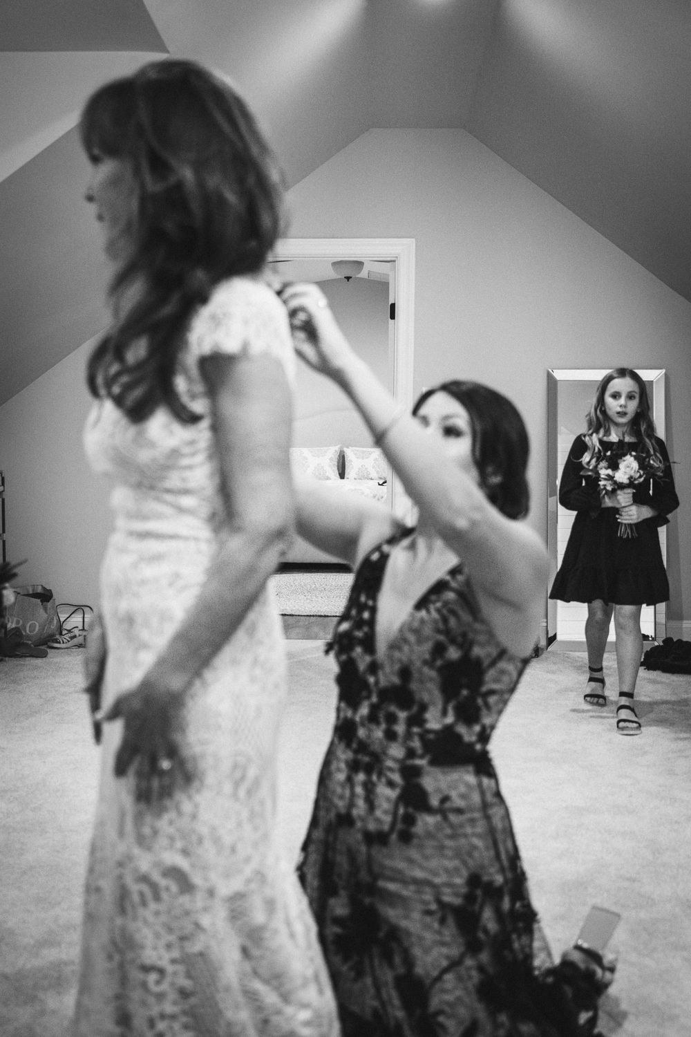 A black and white image of wedding preparations with someone adjusting a dress.