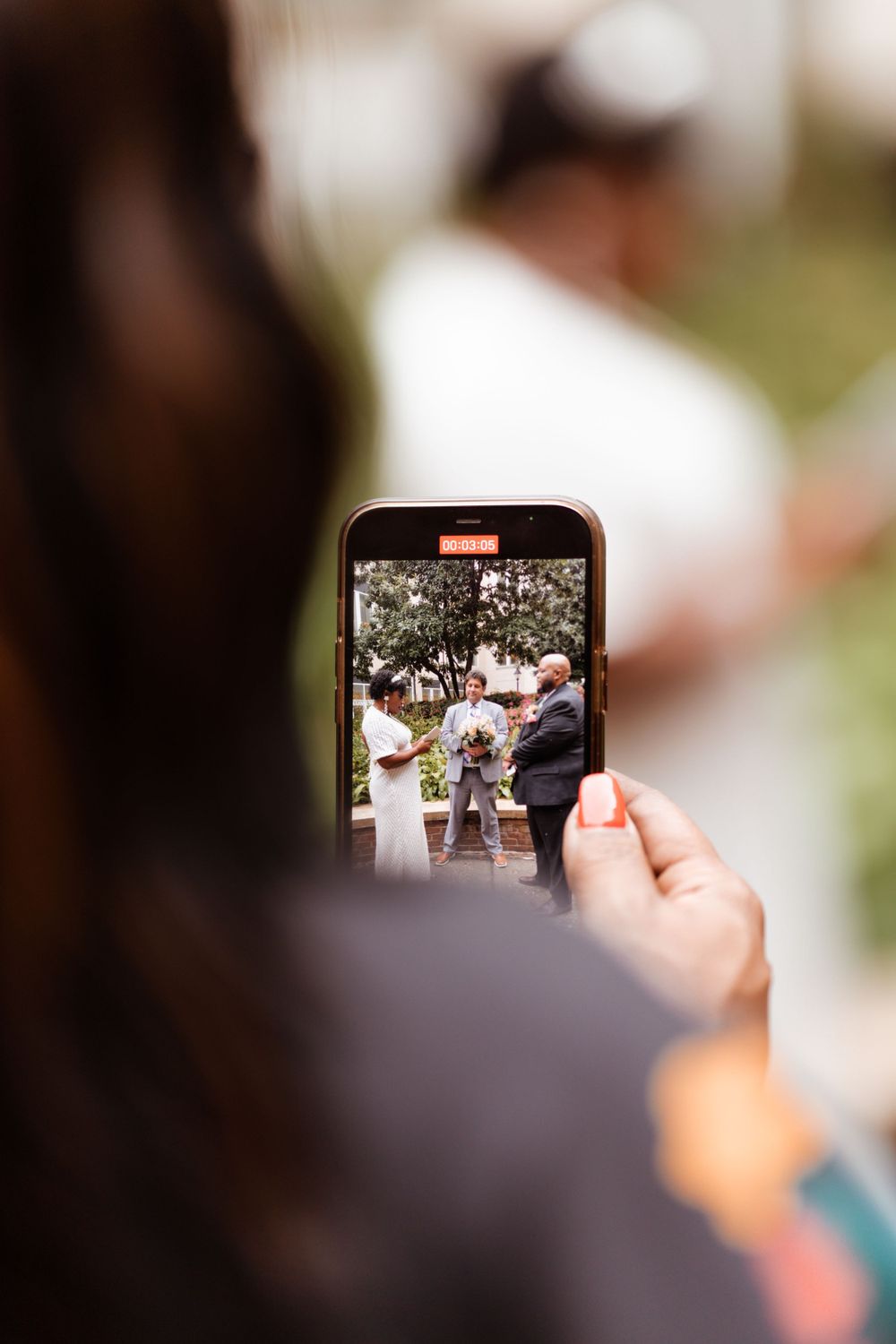 A smartphone captures a wedding ceremony moment through its camera screen.