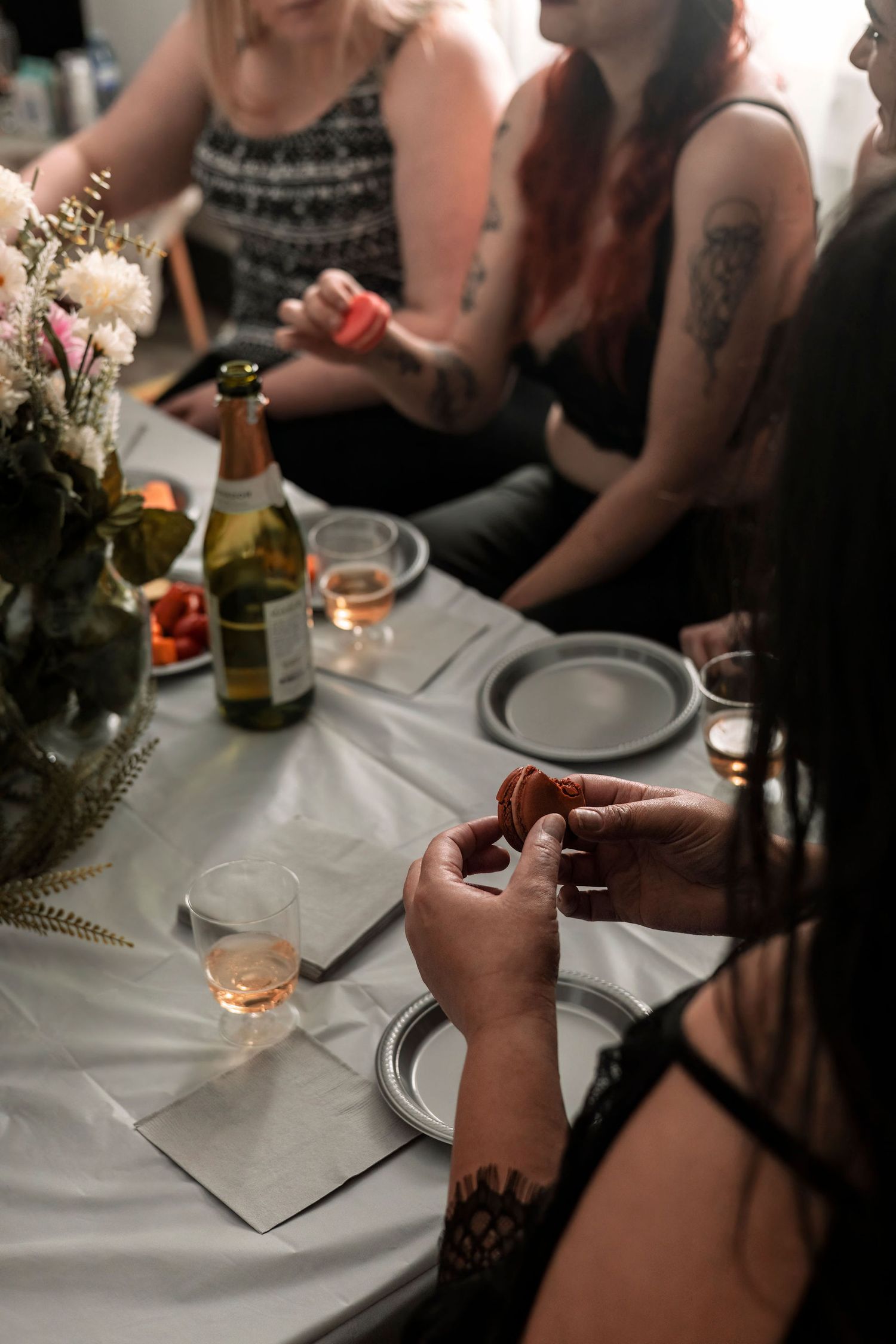 Hands and drinks at an elegant dinner party with white tablecloths and wine glasses.