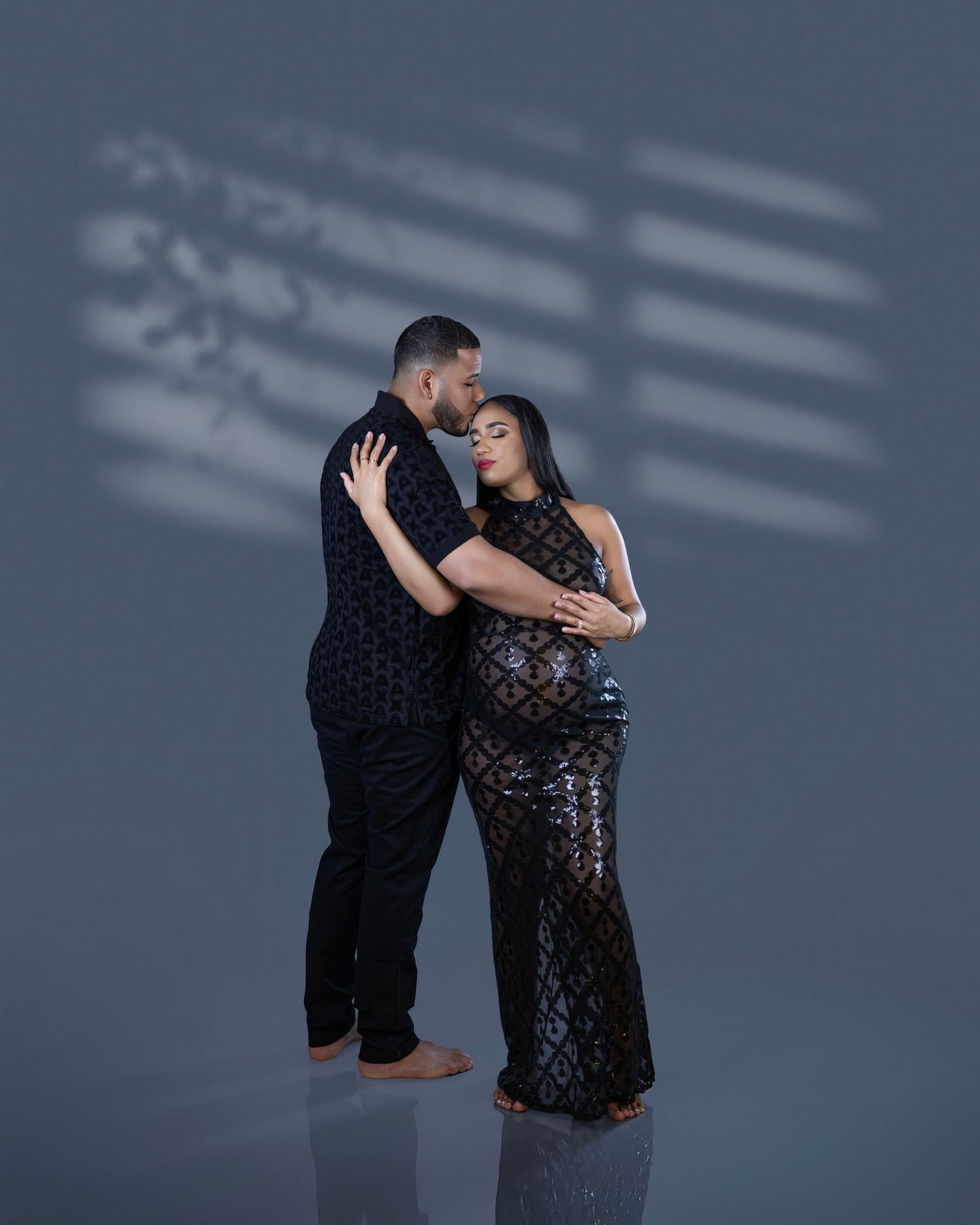 A couple in black outfits sharing an intimate dance pose against a dark background with dramatic lighting.