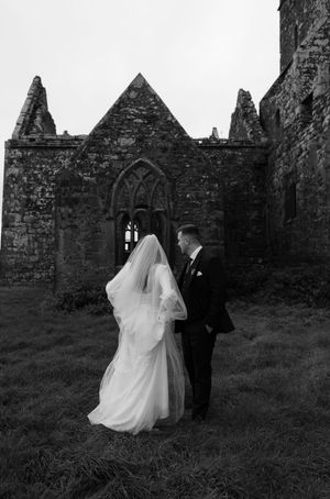 A couple walks through the ruins of an old stone church on their wedding day.