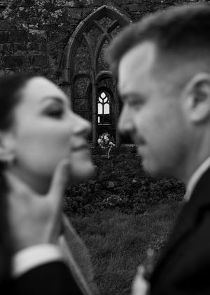 Silhouettes against a stone wall with gothic windows create a dramatic wedding portrait.