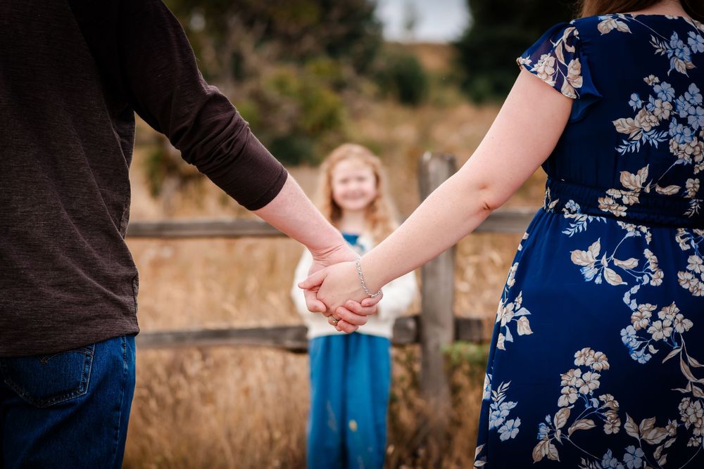 Close-up shot of hands joined together against a blurred natural outdoor background.