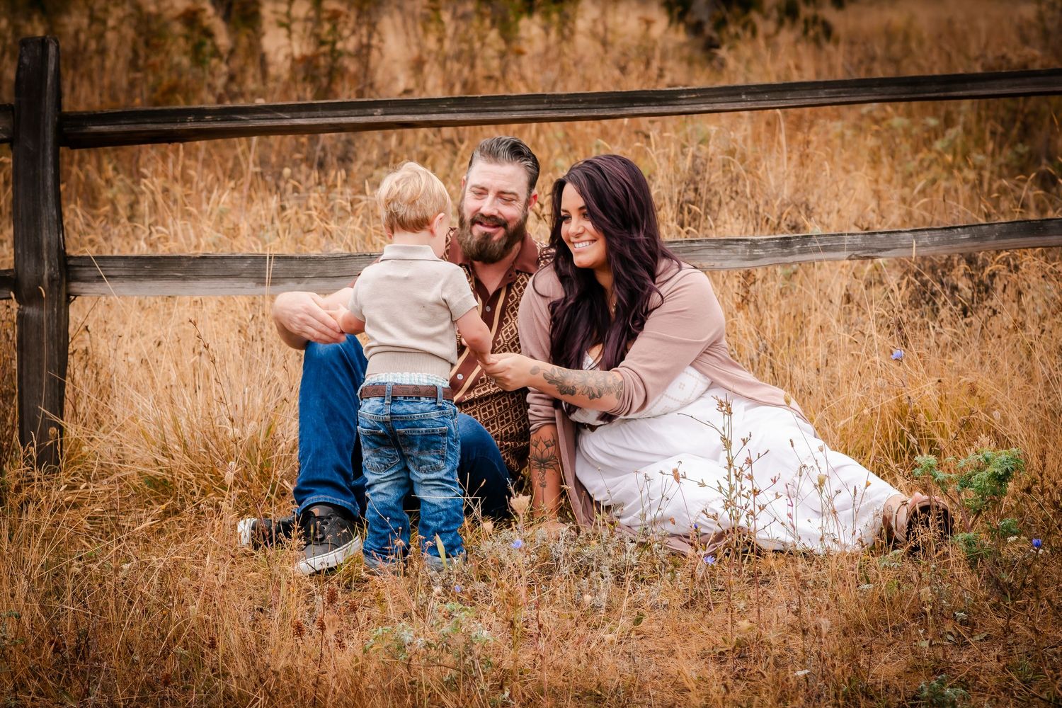 Family enjoying an intimate moment together while sitting on grass during a golden hour outdoor photo session.