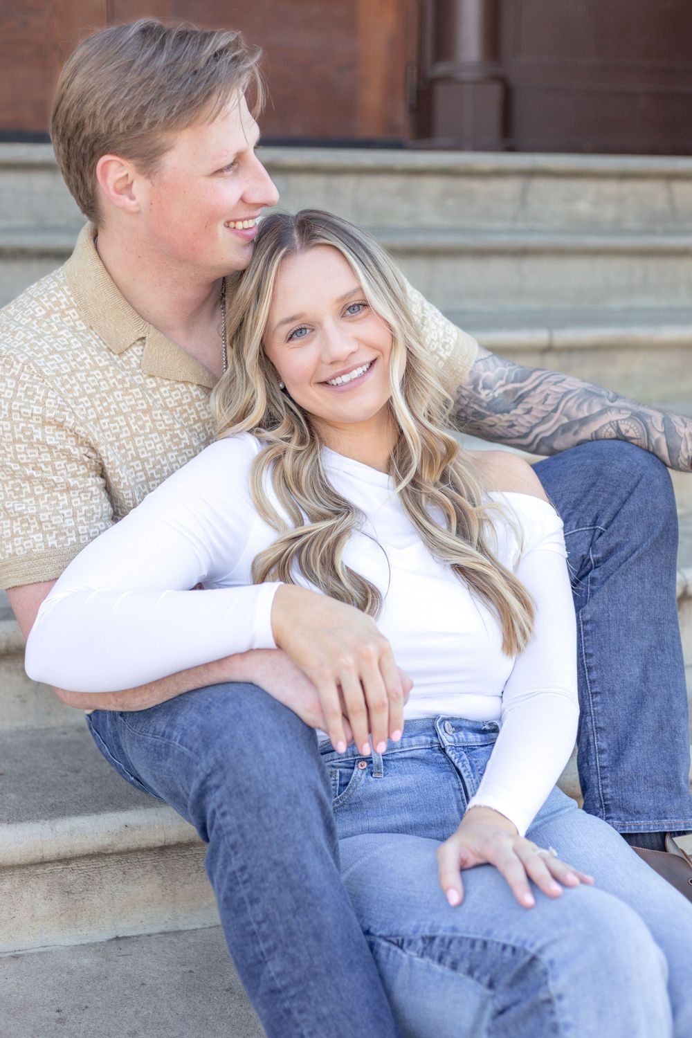 Couple's portrait, featuring the two of them smiling and looking at each other, with a clean background and natural light.