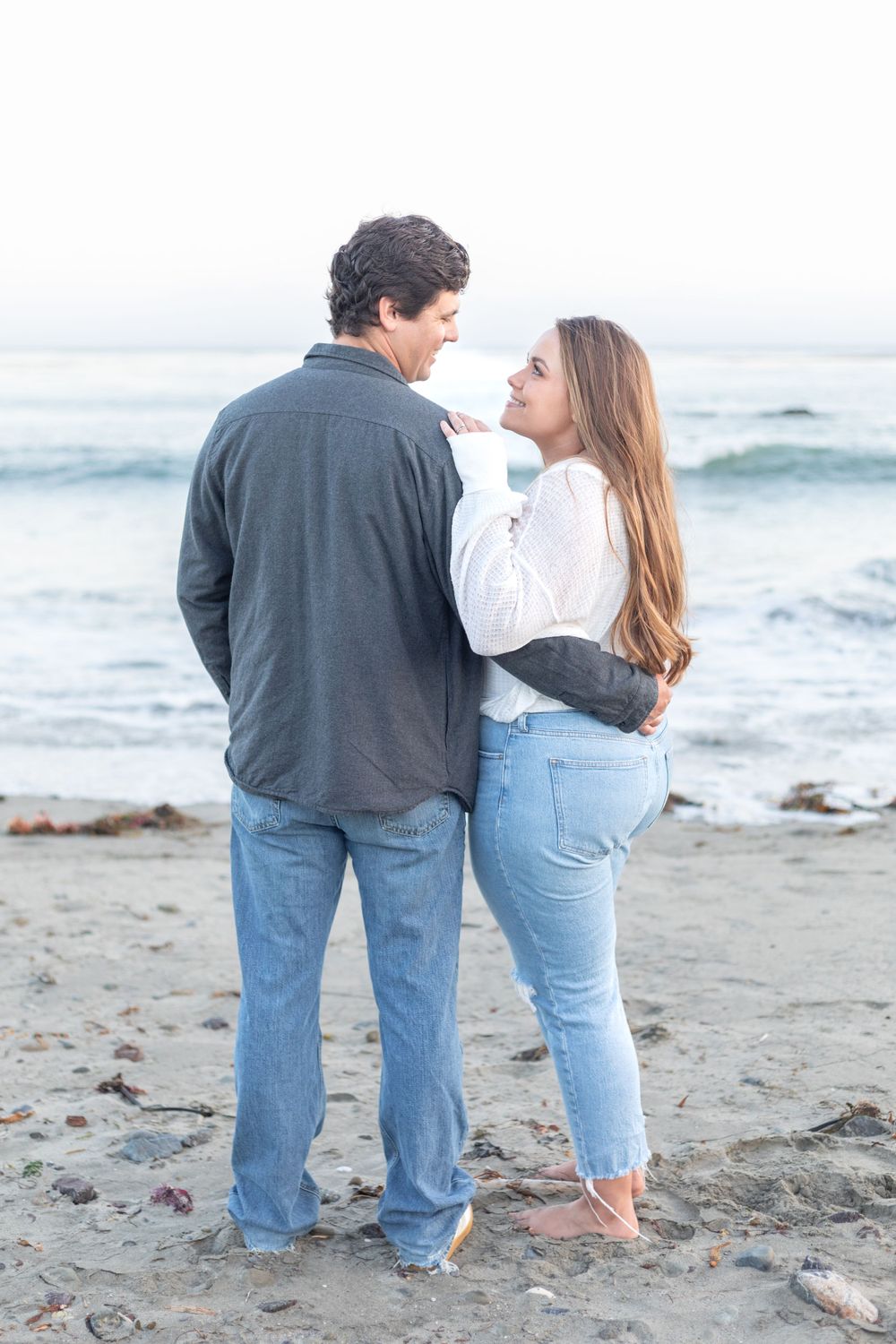 Couple's portrait, featuring the two of them smiling and looking at each other, with a clean background and natural light.