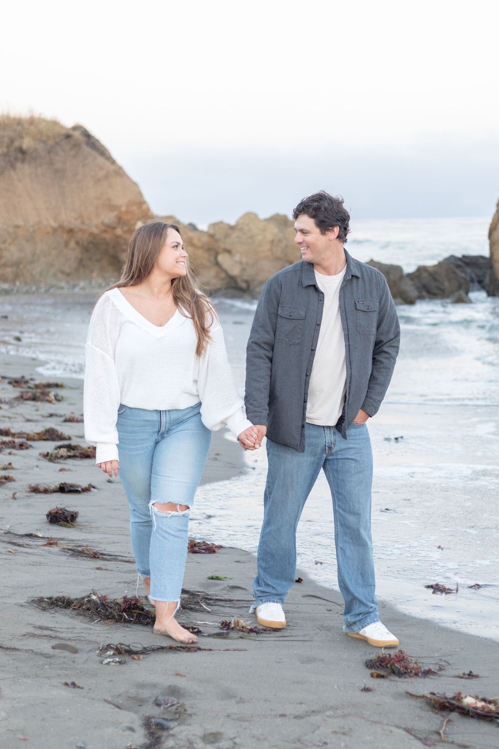 Couple's portrait, featuring the two of them smiling and looking at each other, with a clean background and natural light.