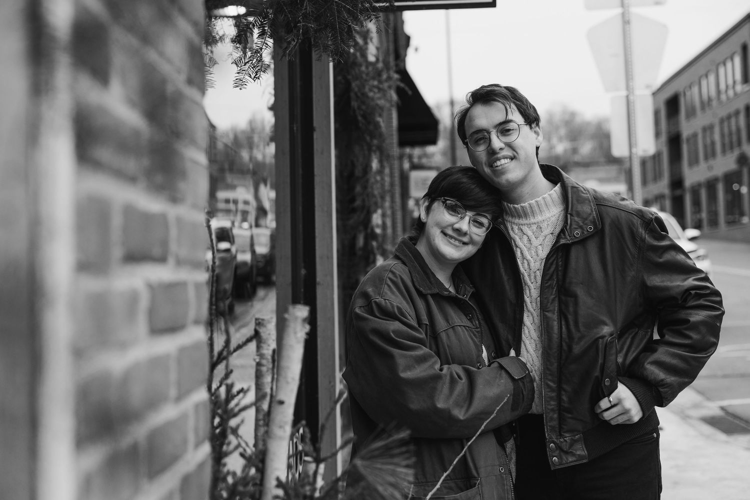 Vintage black and white photograph of couple against brick wall exterior.