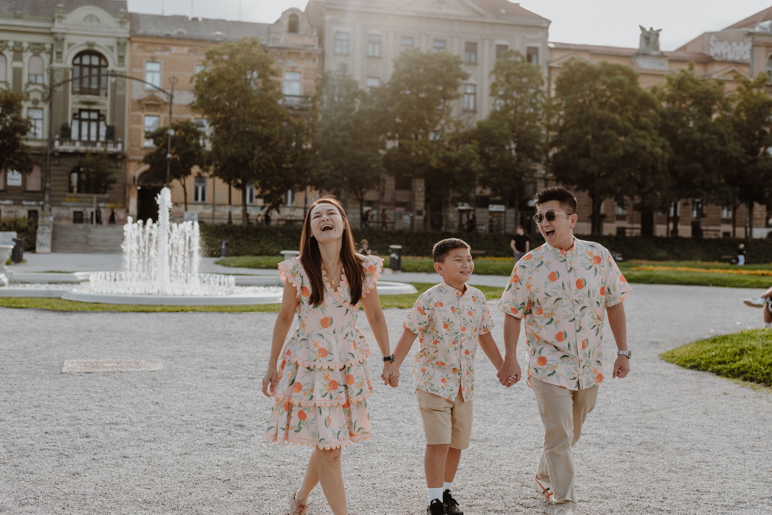 Family members in coordinated floral outfits walking together near a fountain.