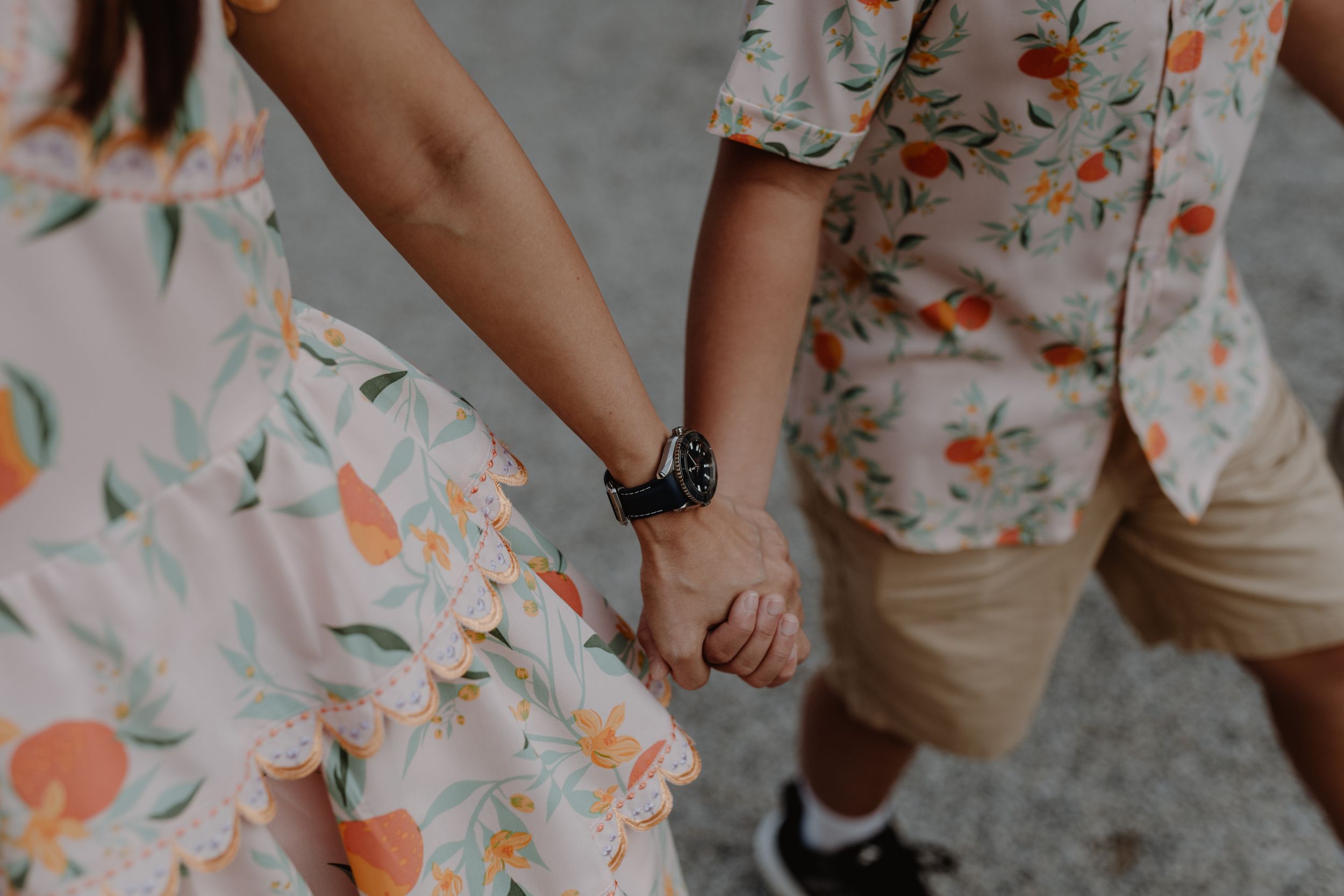 Close-up detail of matching floral print outfits and held hands while walking.