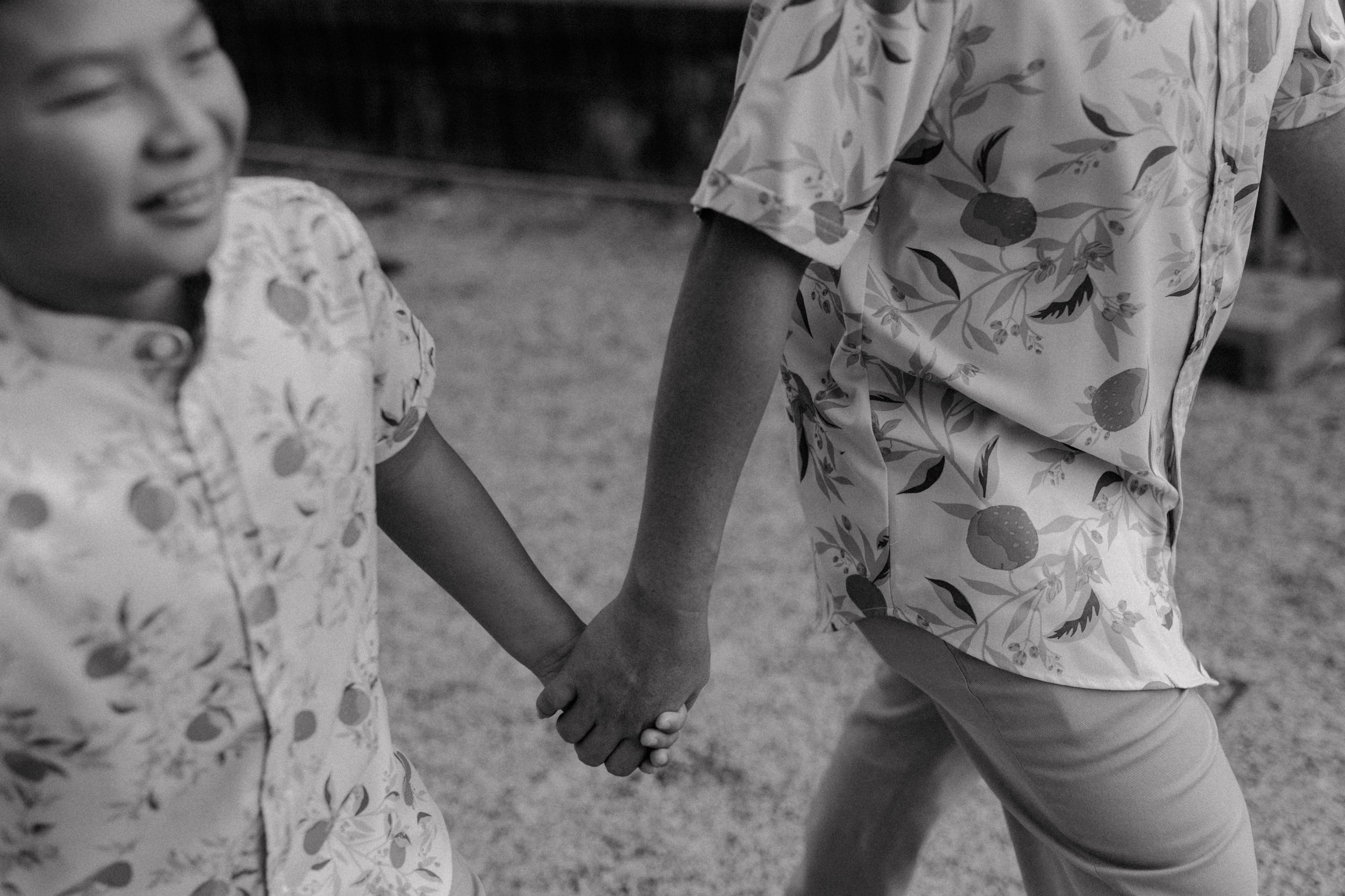 Black and white photo showing joined hands of people wearing matching floral prints.