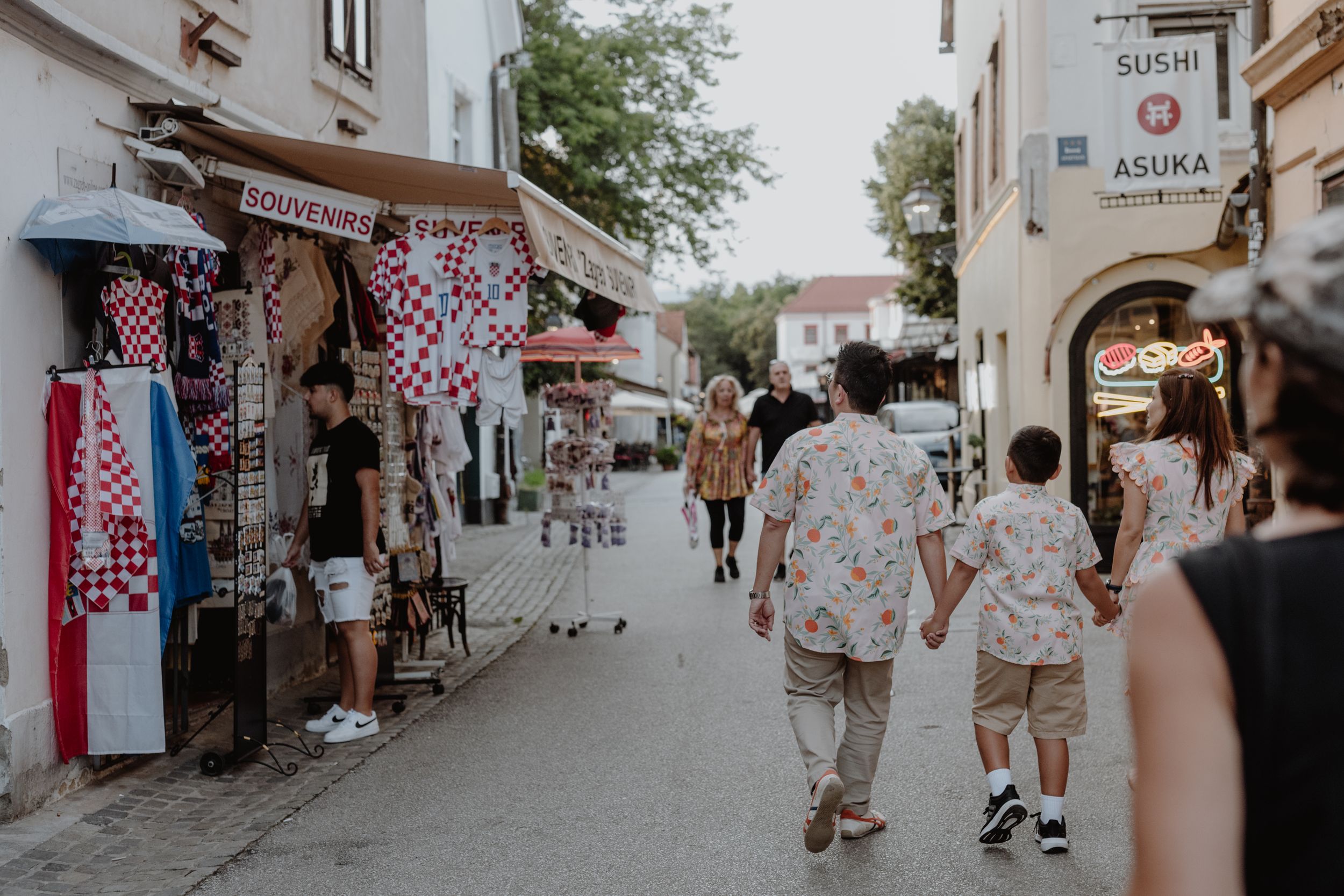 Family walking through a colorful street market in Zagreb during vacation photoshoot.