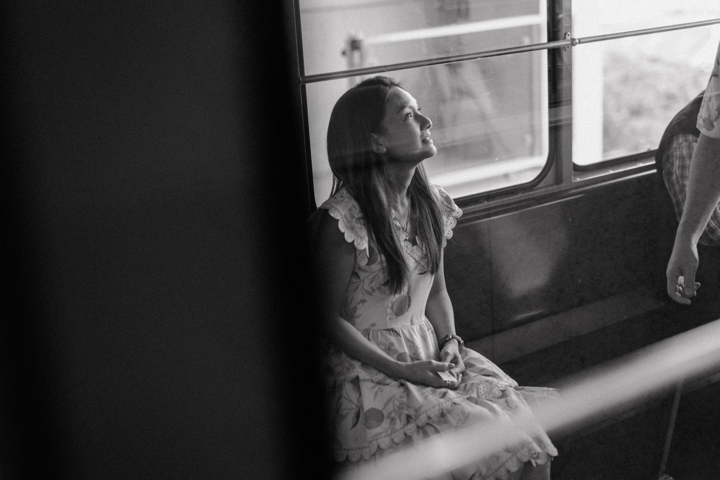 Black and white portrait of mom in the funicular, gazing out the window with a soft smile.