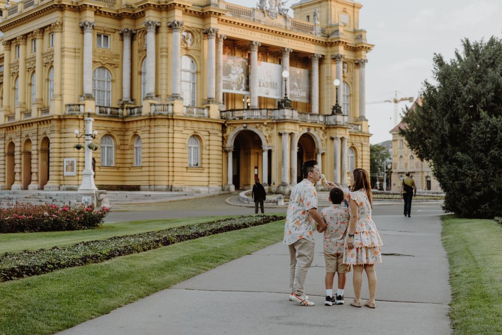 Wide shot of a family enjoying ice cream together, with the iconic Croatian National Theatre in the background.