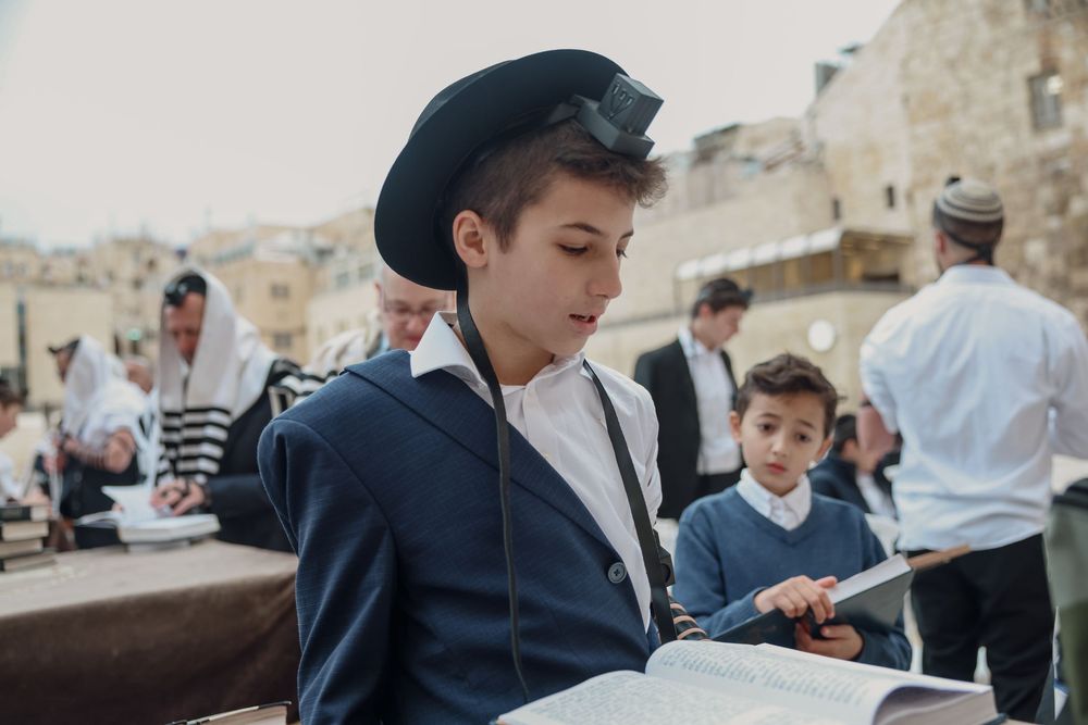 Young Jewish boy reading from a religious text at the Western Wall in Jerusalem.