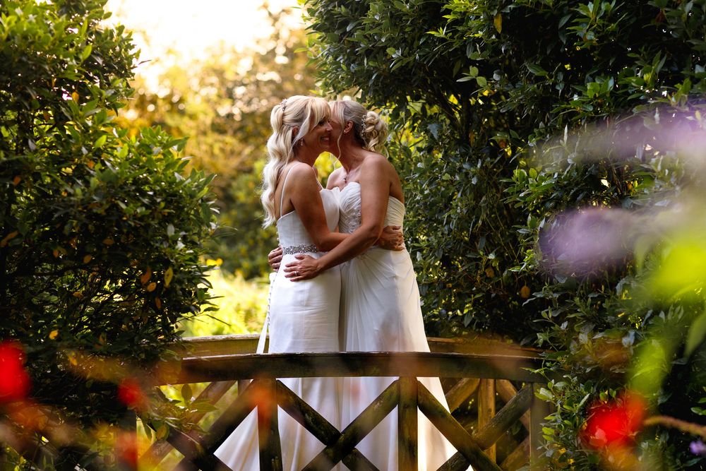 A couple embraces tenderly in a romantic garden setting during sunset with soft natural lighting and foliage in the background.