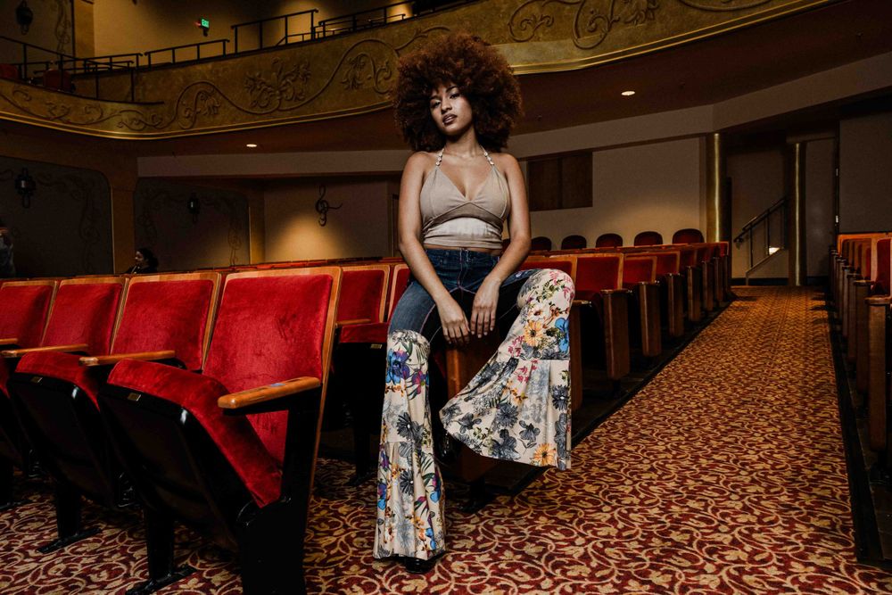 Retro-inspired portrait in historic theater with patterned bell-bottom jeans.