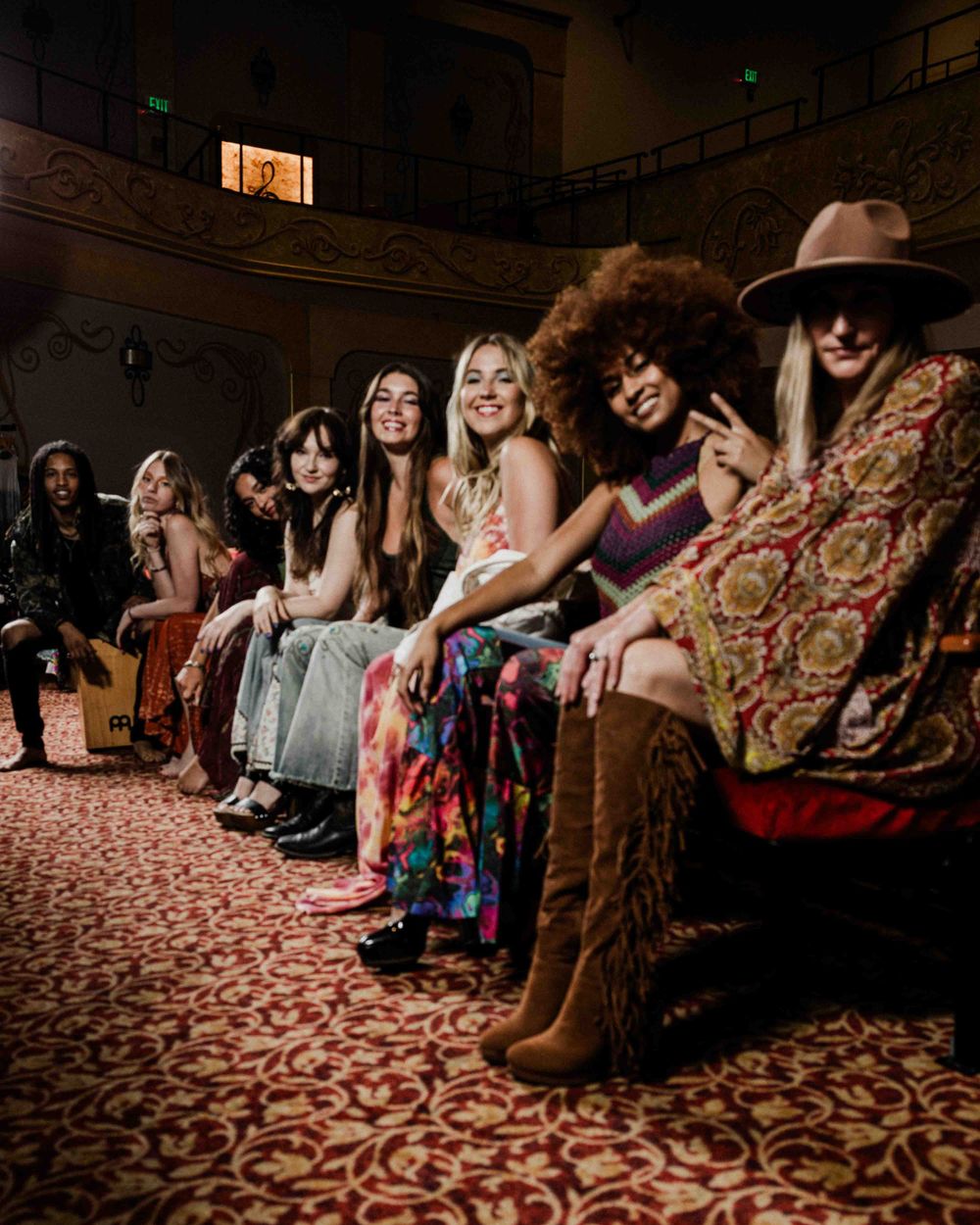 Group seated in ornate theater wearing colorful bohemian fashion.