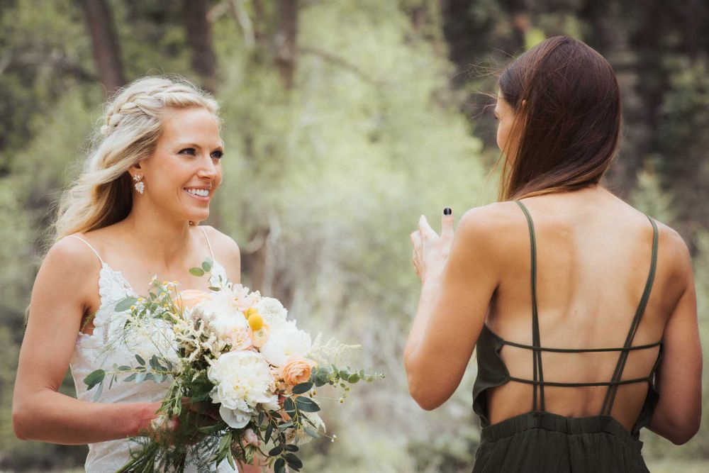Two people share a joyful moment outdoors with white floral bouquets.