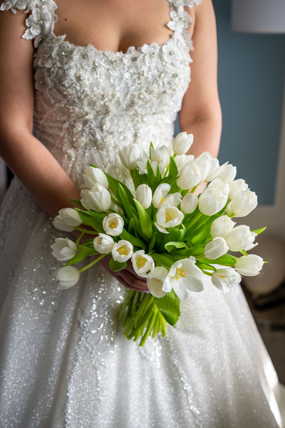 Beautiful white tulip bridal bouquet held against a lace wedding dress.