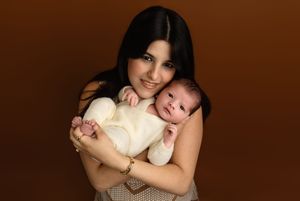 Lovely, dark-haired mama proudly cuddles her newborn baby boy against a mocha backdrop, by Charlottesville newborn and family photographer.
