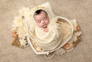 Sweet baby girl sleeps wrapped in white in a heart bowl, adorned by florals and lace during her Charlottesville newborn photography session.