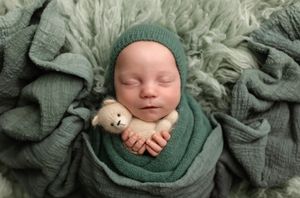 Baby boy sleeps, wrapped in turquoise knits and holding a soft teddy, captured by Charlottesville newborn and maternity photographer.