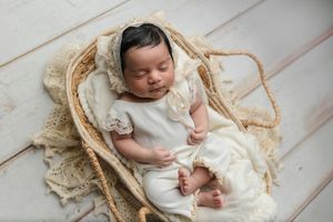 Baby dressed in a white romper and lace bear-ear hat sleeps in a Moses basket, captured by Charlottesville newborn and family photographer.