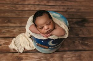 Charlottesville newborn and family photographer captured a dark-haired baby boy sleeping soundly in a in a moon-themed bucket.