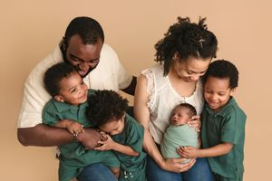 Family with four young sons laugh together for their newborn session, captured by Charlottesville newborn and baby photographer.