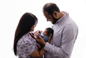 Backlit new parents lovingly cradle their son, who looks back at them, captured by charlottesville family and newborn photographer.