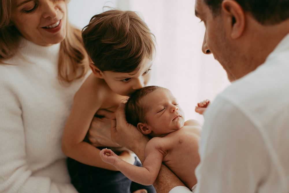 Collage of tender family moments showing parents embracing and cuddling with their sleeping baby in soft lighting.