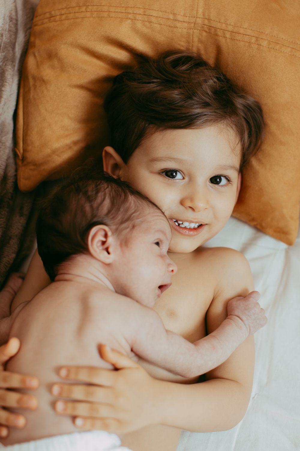 A baby lies on cream-colored bedding while stretching and yawning in a series of connected photos.