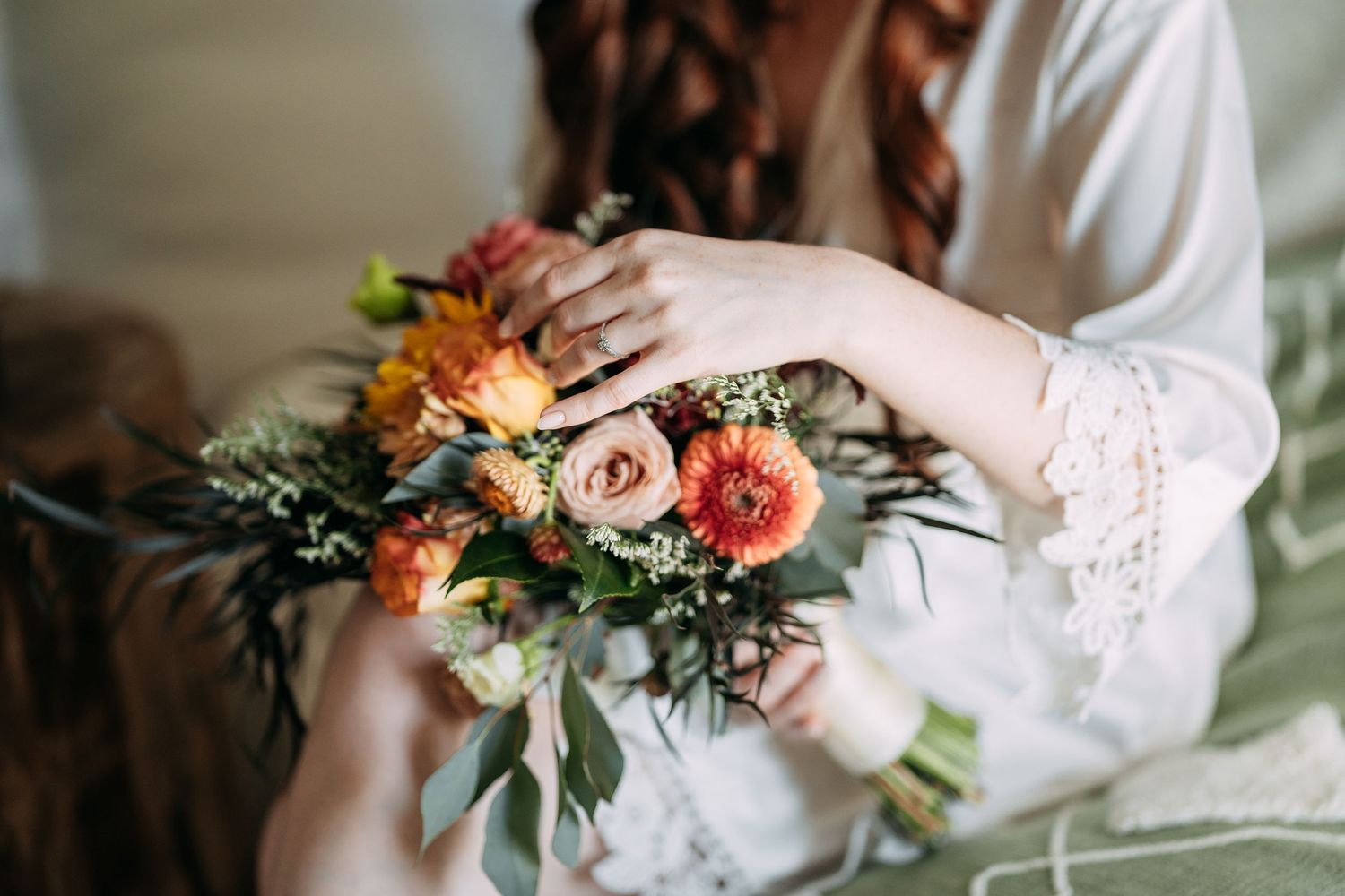 Delicate coral and peach floral bouquet with greenery against a soft white background.