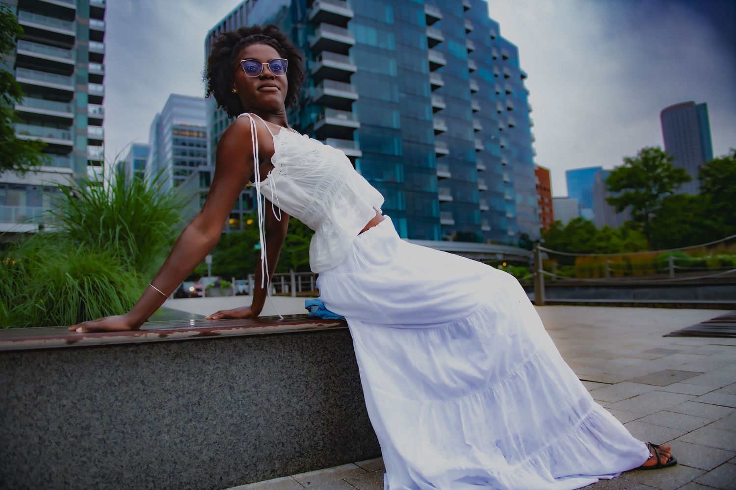 Urban fashion photo with white dress against modern apartment buildings.