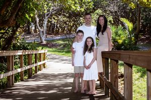 Family walking along a wooden boardwalk path through lush greenery.