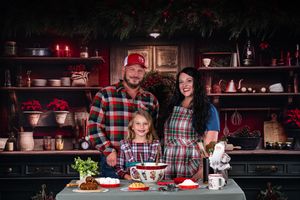 Family gathered around rustic wooden table with Christmas decorations and treats.