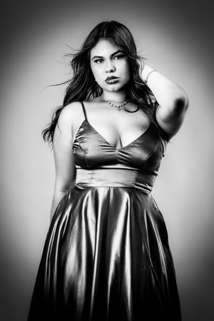 Black and white fashion portraits showing curves in metallic dress against studio backdrop.
