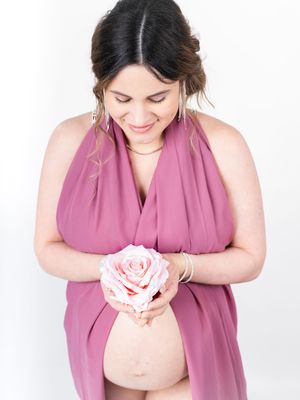 Maternity photo series showing woman in mauve dress holding pink rose.